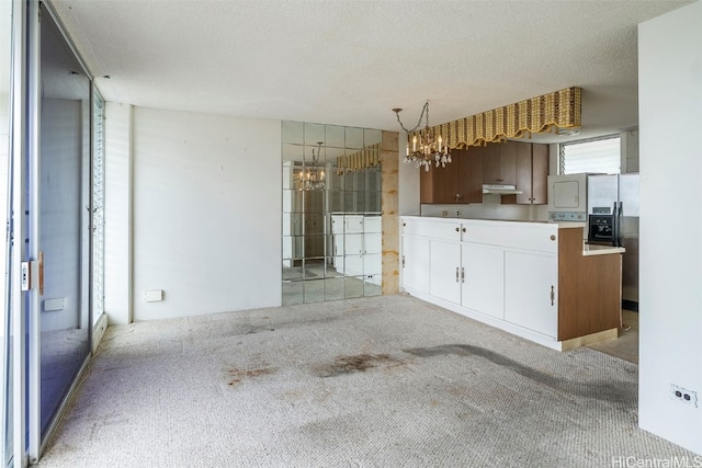 kitchen with stainless steel fridge, an inviting chandelier, a textured ceiling, decorative light fixtures, and light colored carpet