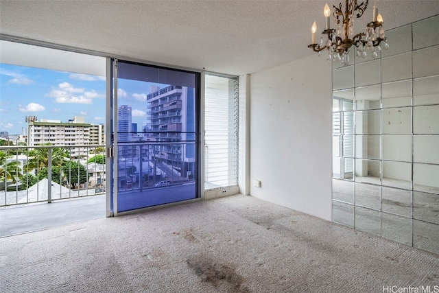 carpeted spare room featuring expansive windows, plenty of natural light, a chandelier, and a textured ceiling