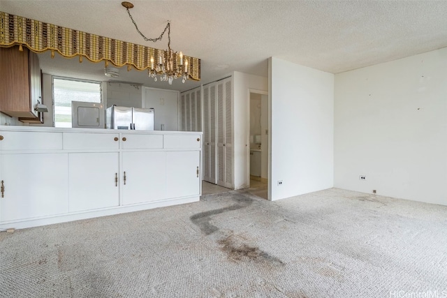 interior space featuring a notable chandelier, light colored carpet, and a textured ceiling