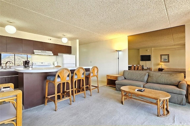 kitchen with light carpet, range, white fridge, dark brown cabinetry, and a breakfast bar area