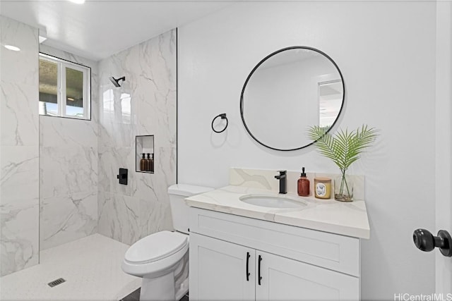 bathroom featuring a tile shower, vanity, and toilet