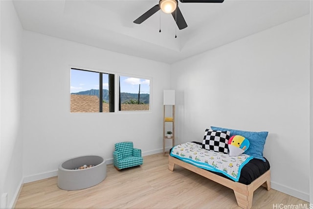 sitting room with a raised ceiling, light hardwood / wood-style flooring, and ceiling fan