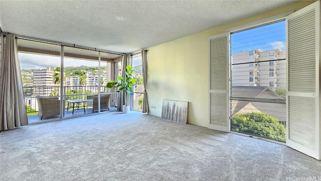 carpeted spare room featuring floor to ceiling windows and a textured ceiling