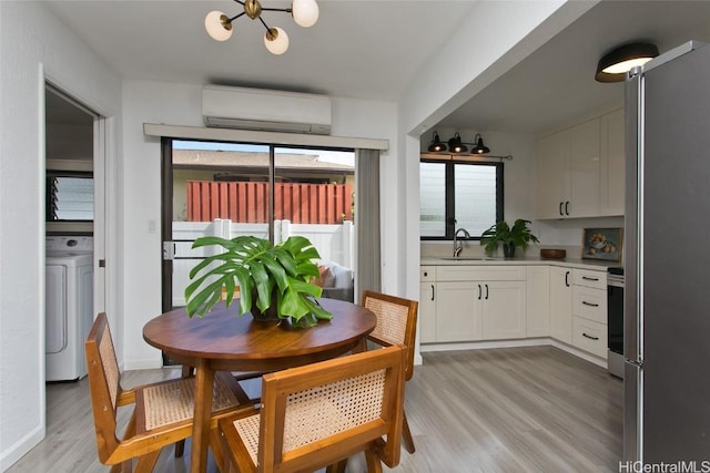 dining space featuring an inviting chandelier, washer / dryer, light hardwood / wood-style flooring, and a wall mounted AC