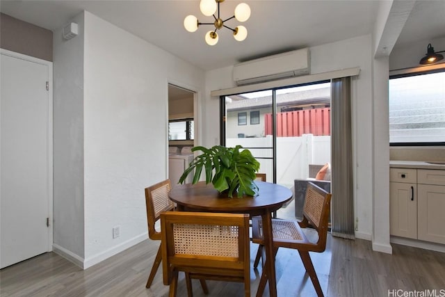 dining room featuring a notable chandelier, washer / clothes dryer, light wood-type flooring, and a wall unit AC