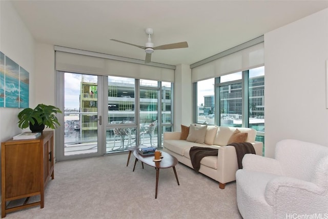 living room with ceiling fan, expansive windows, and light colored carpet