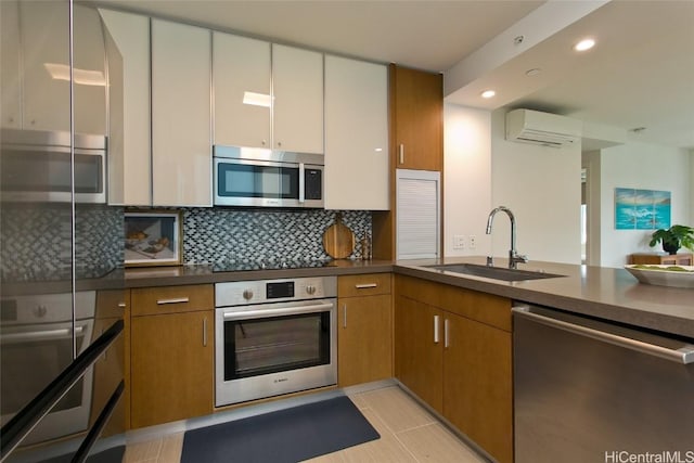 kitchen with sink, tasteful backsplash, a wall mounted AC, and stainless steel appliances