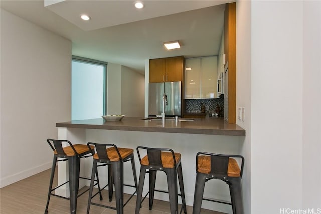 kitchen featuring kitchen peninsula, a kitchen bar, and stainless steel refrigerator