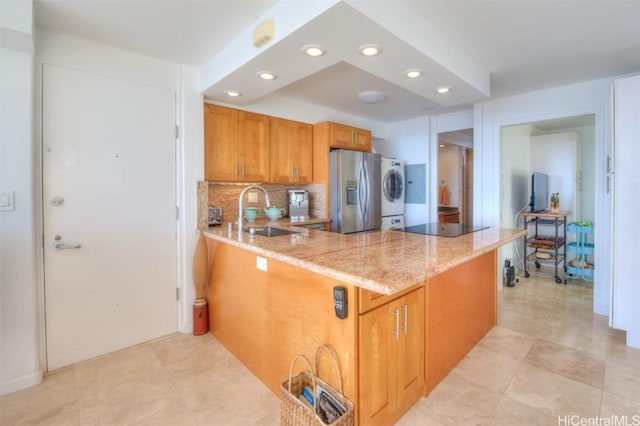 kitchen featuring kitchen peninsula, stainless steel refrigerator with ice dispenser, stacked washer and dryer, and sink