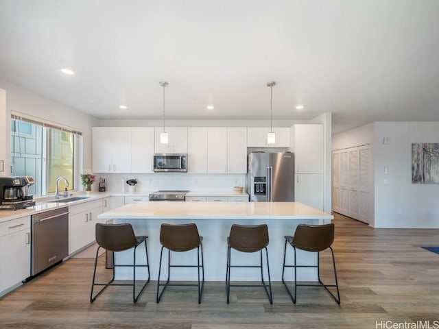 kitchen featuring a center island, white cabinets, hanging light fixtures, and appliances with stainless steel finishes