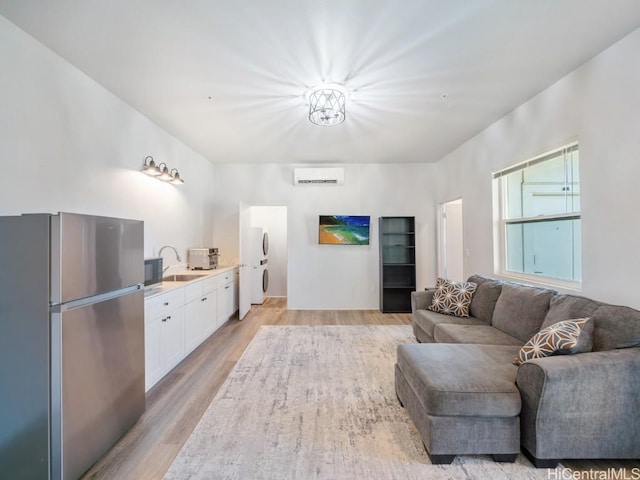 living room featuring a wall unit AC, sink, and light hardwood / wood-style floors