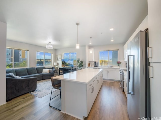 kitchen featuring white cabinets, a kitchen island, a healthy amount of sunlight, and stainless steel appliances