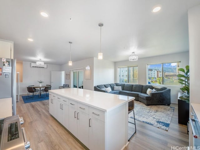 kitchen with white cabinetry, hanging light fixtures, a notable chandelier, light hardwood / wood-style floors, and a kitchen island