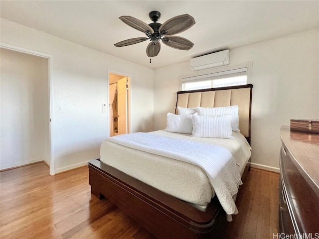 bedroom featuring hardwood / wood-style floors, connected bathroom, a wall mounted AC, and ceiling fan