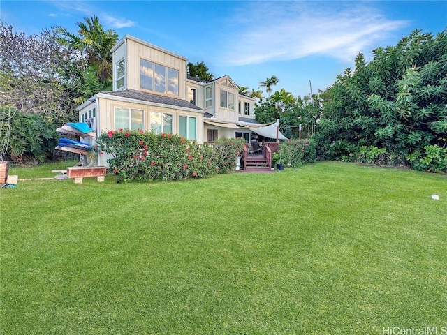 rear view of property with a deck and a yard