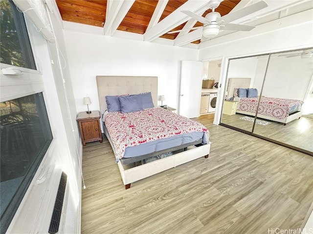 bedroom featuring beam ceiling, washer / clothes dryer, wooden ceiling, a closet, and light wood-type flooring