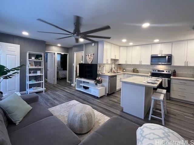 kitchen featuring dark wood-type flooring, sink, a kitchen island, white cabinetry, and stainless steel appliances