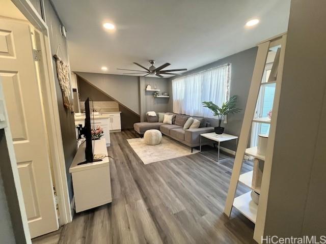 living room featuring ceiling fan and dark wood-type flooring