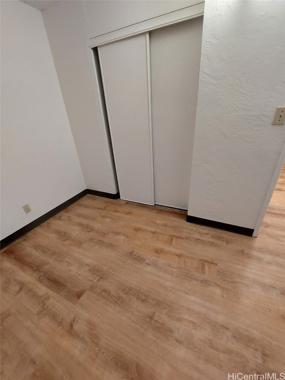 unfurnished bedroom with a closet and light wood-type flooring