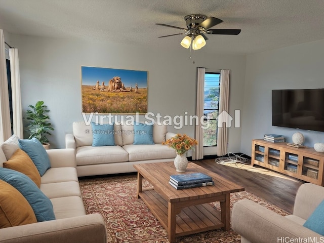 living room with ceiling fan, dark wood-type flooring, and a textured ceiling