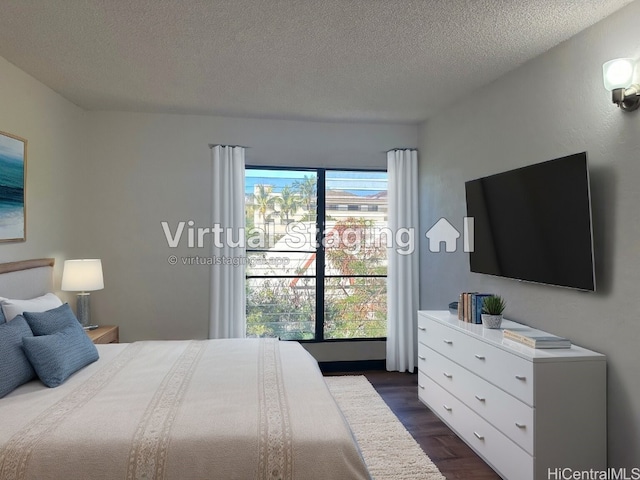 bedroom with a textured ceiling, dark hardwood / wood-style floors, and multiple windows