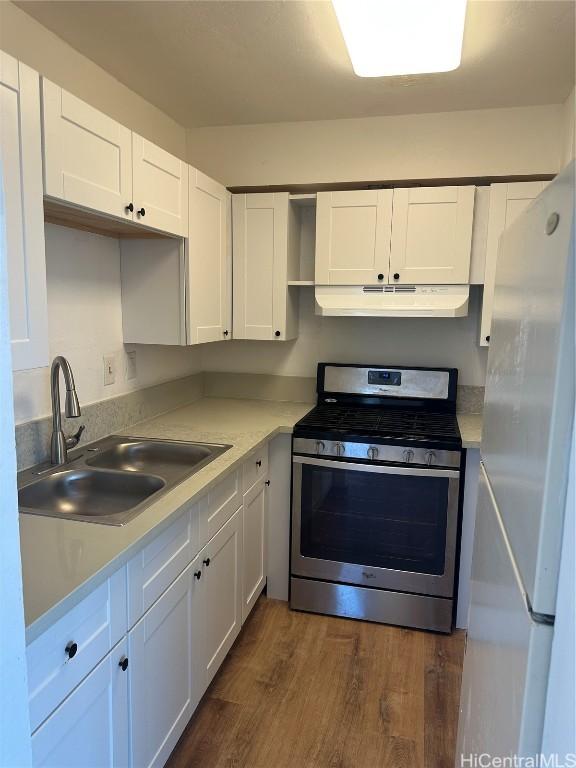 kitchen with sink, stainless steel stove, dark hardwood / wood-style flooring, white fridge, and white cabinets