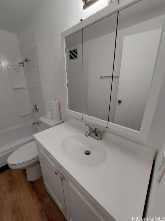 full bathroom with vanity, hardwood / wood-style flooring, toilet, and  shower combination