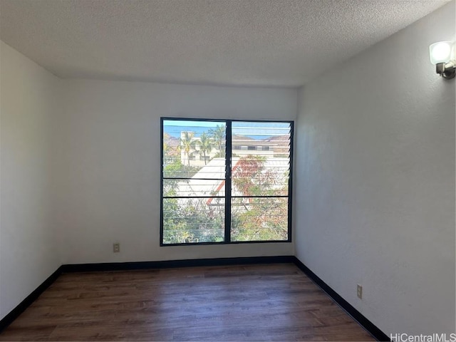 empty room featuring a wealth of natural light, dark hardwood / wood-style flooring, and a textured ceiling