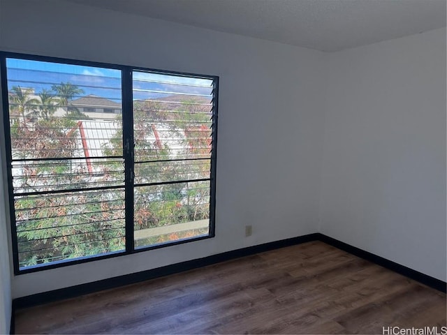 unfurnished room with plenty of natural light and dark hardwood / wood-style floors