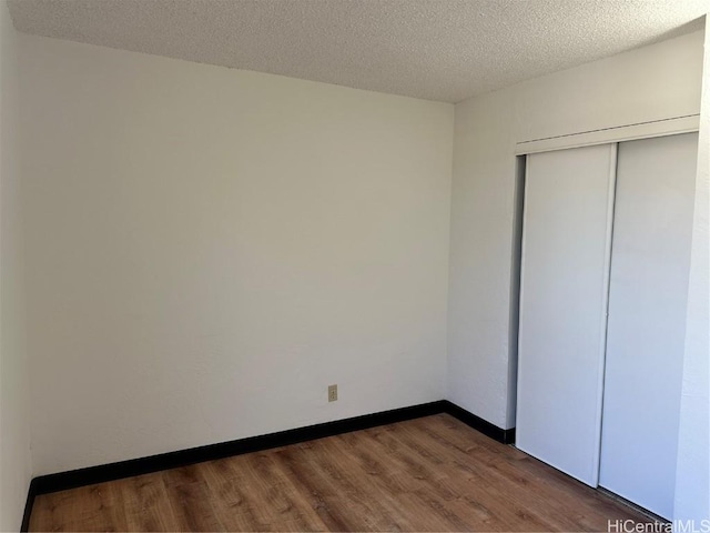 unfurnished bedroom featuring dark hardwood / wood-style floors, a textured ceiling, and a closet