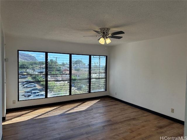 spare room featuring ceiling fan, dark wood-type flooring, and a healthy amount of sunlight