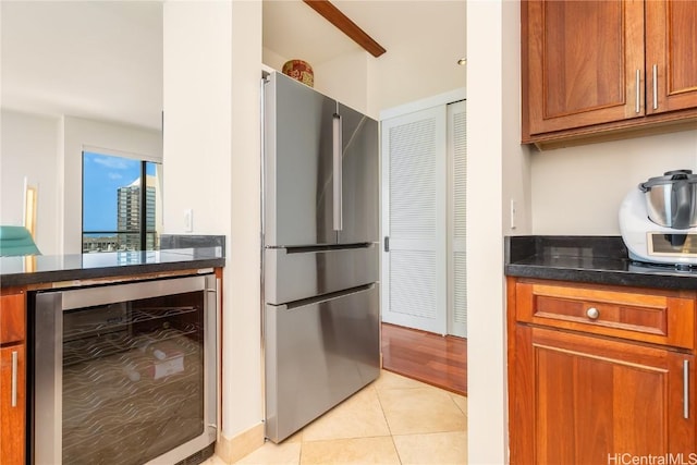 kitchen with dark stone counters, stainless steel refrigerator, light tile patterned floors, and beverage cooler