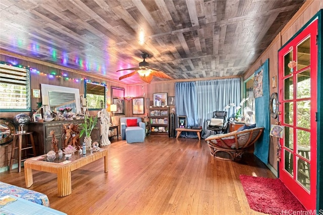 living area with ceiling fan, wooden ceiling, wood walls, and wood-type flooring