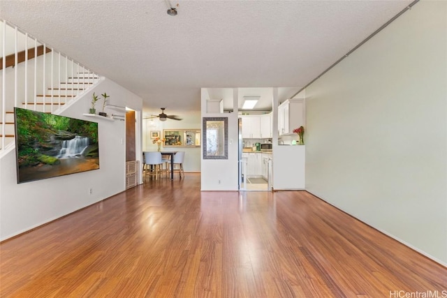 unfurnished living room featuring a textured ceiling, ceiling fan, and wood-type flooring