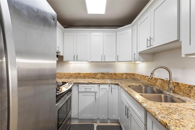 kitchen featuring white cabinetry, stainless steel appliances, sink, light stone counters, and light tile patterned floors