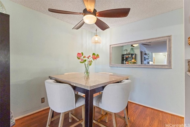 dining area with ceiling fan, wood-type flooring, and a textured ceiling