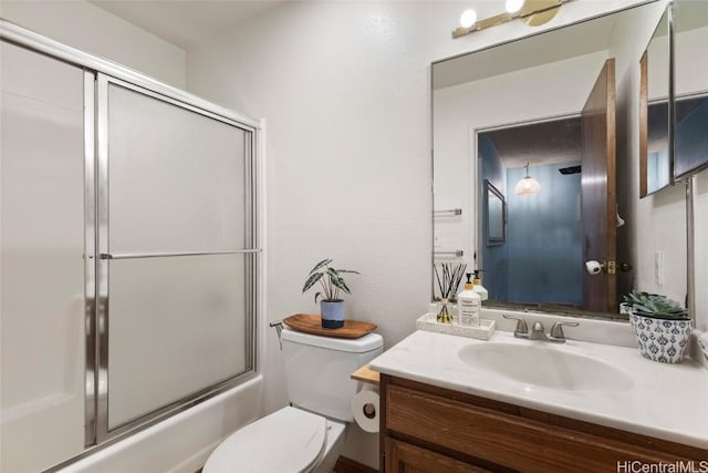 full bathroom with enclosed tub / shower combo, vanity, and toilet