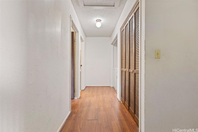 hall featuring a textured ceiling and light hardwood / wood-style flooring