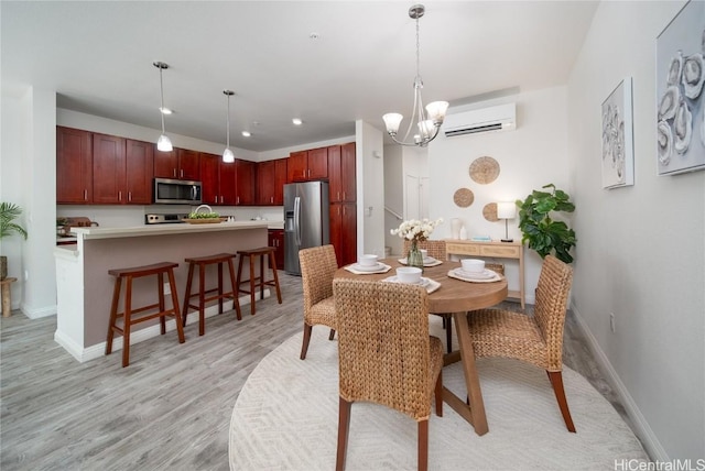 dining space featuring a wall unit AC, light hardwood / wood-style floors, and an inviting chandelier