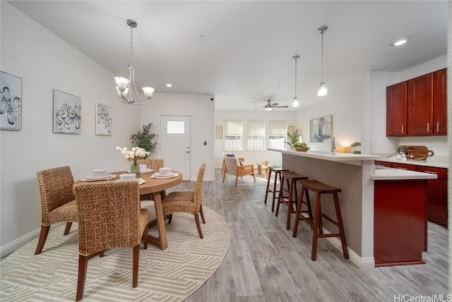 dining area featuring ceiling fan with notable chandelier and light hardwood / wood-style floors