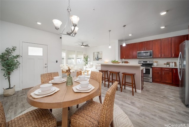 dining area featuring ceiling fan with notable chandelier and light hardwood / wood-style flooring