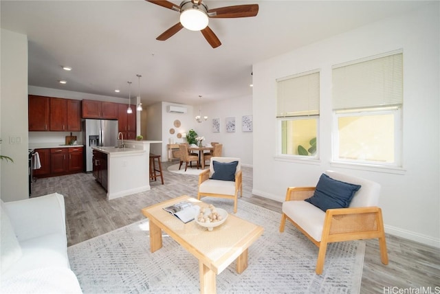 living room with ceiling fan, sink, light hardwood / wood-style floors, and a wall mounted air conditioner