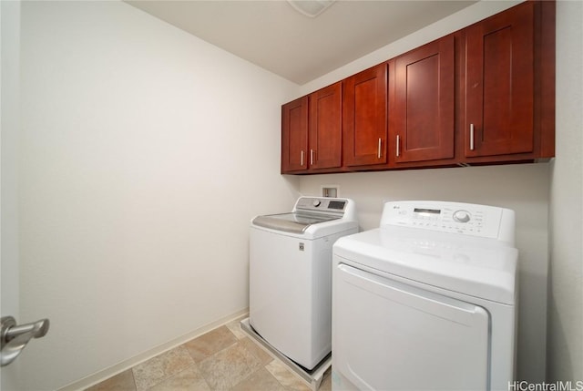 clothes washing area with cabinets and washing machine and clothes dryer