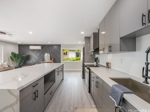 kitchen with gray cabinets, light stone countertops, stainless steel range with electric cooktop, and light hardwood / wood-style floors