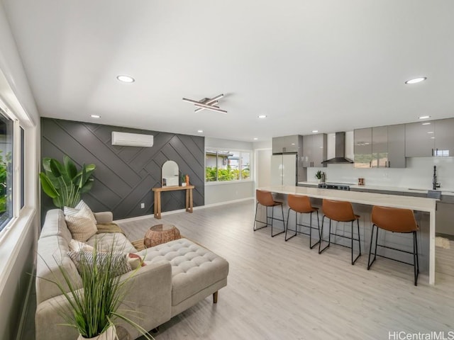 living room with light hardwood / wood-style flooring and an AC wall unit