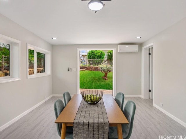 dining room featuring a wall mounted air conditioner and light hardwood / wood-style flooring