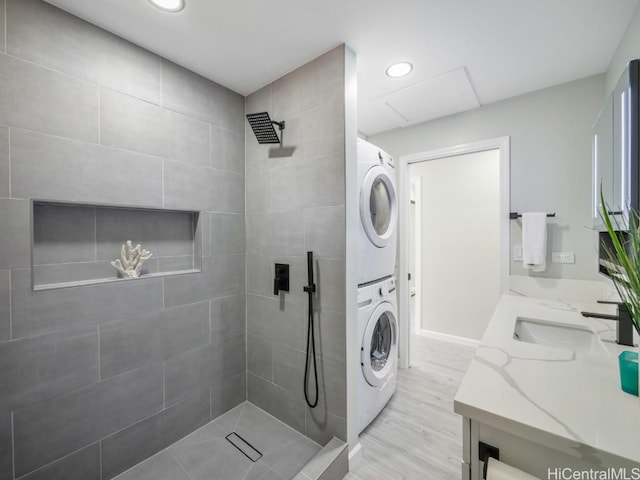 bathroom featuring a tile shower, vanity, and stacked washer / drying machine