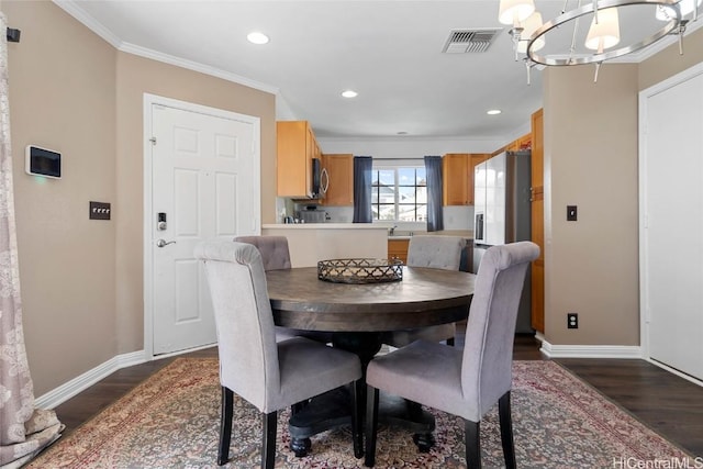 dining room with dark wood-type flooring, an inviting chandelier, ornamental molding, and sink