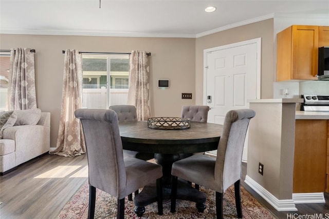 dining space featuring light wood-type flooring and ornamental molding