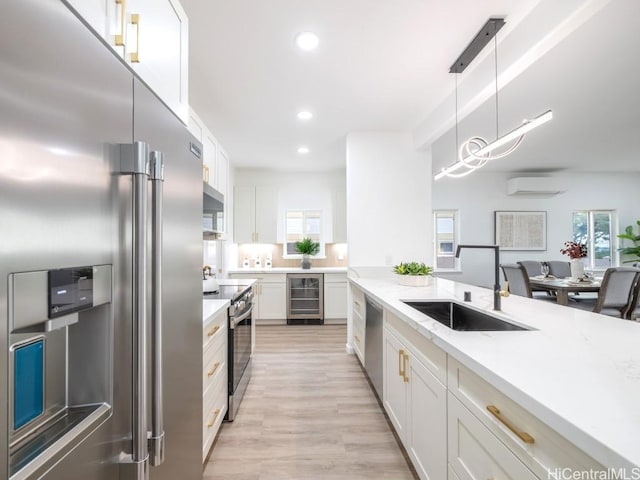 kitchen with white cabinets, appliances with stainless steel finishes, wine cooler, and sink